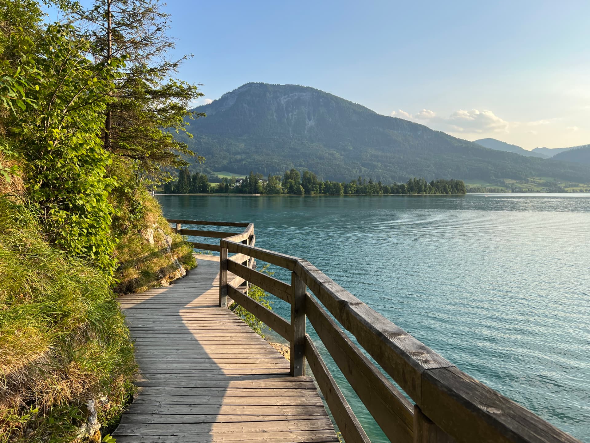 Passerelle en bois au bord d'un lac turquoise, montagne et ciel bleu par un beau jour d'été